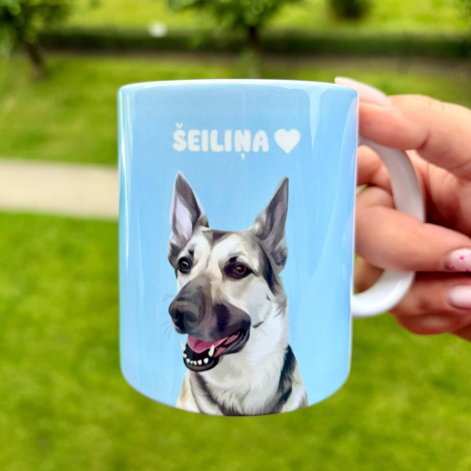 Close up photo of blue custom pet portrait ceramic mug with grey and white dog   on it called Šeiliņa
