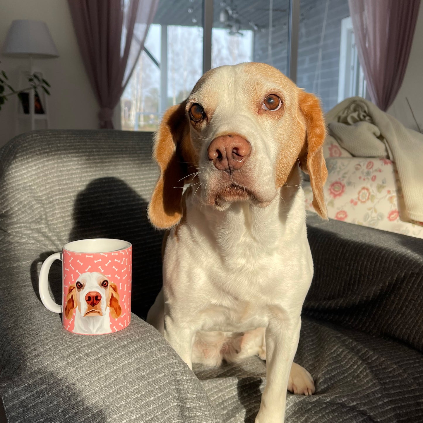 Photo of custom pet portrait ceramic mug with dog's artwork on it sitting next to the actual dog that is beagle