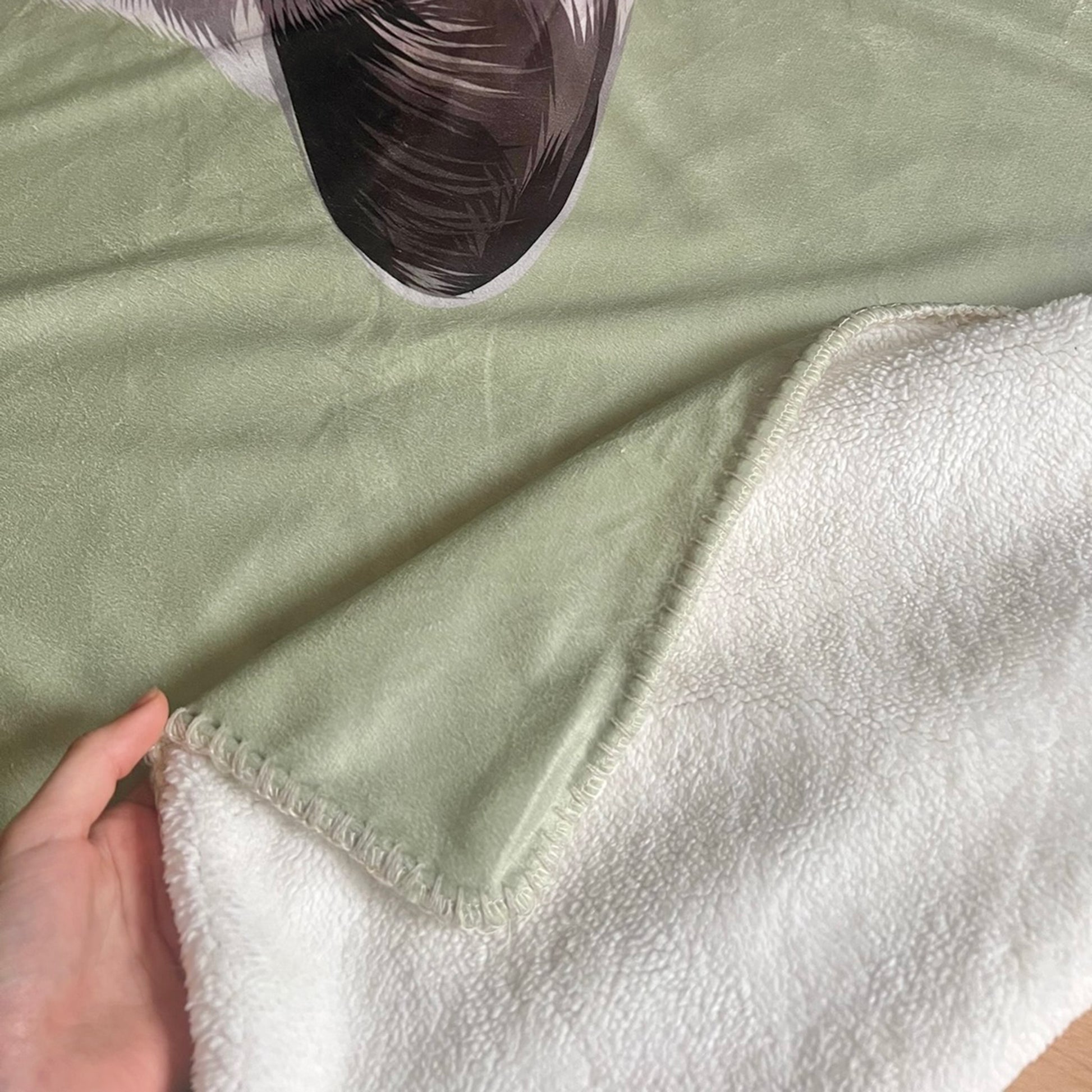 Close up photo of custom pet portrait fleece blanket's inner sewing featuring ultra soft microfiber fleece interior and decorative blanket stitching on the edge pf the blanket.