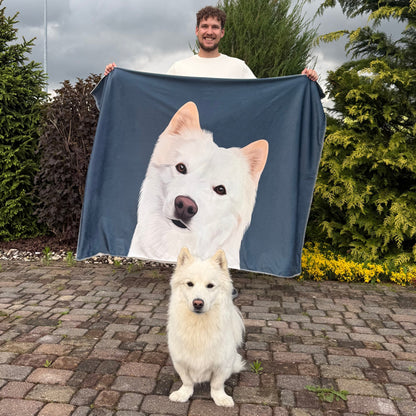 Photo of man holding custom pet portait fleece blanket in charcoal color with white dog's artwork on it and in the front of them are sitting the actual white dog.