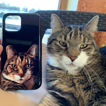 Photo of black custom pet portrait tough phone case with cat's artwork on it next to the actual cat