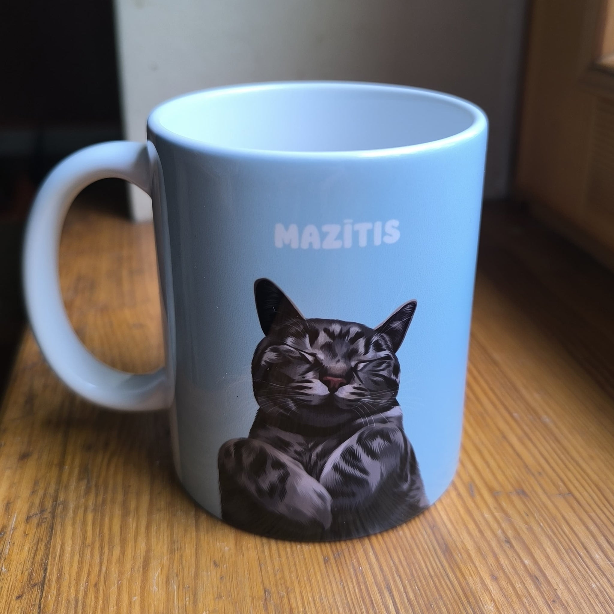 Close-up photo of custom pet portrait ceramic mug featuring grey cat called Mazītis