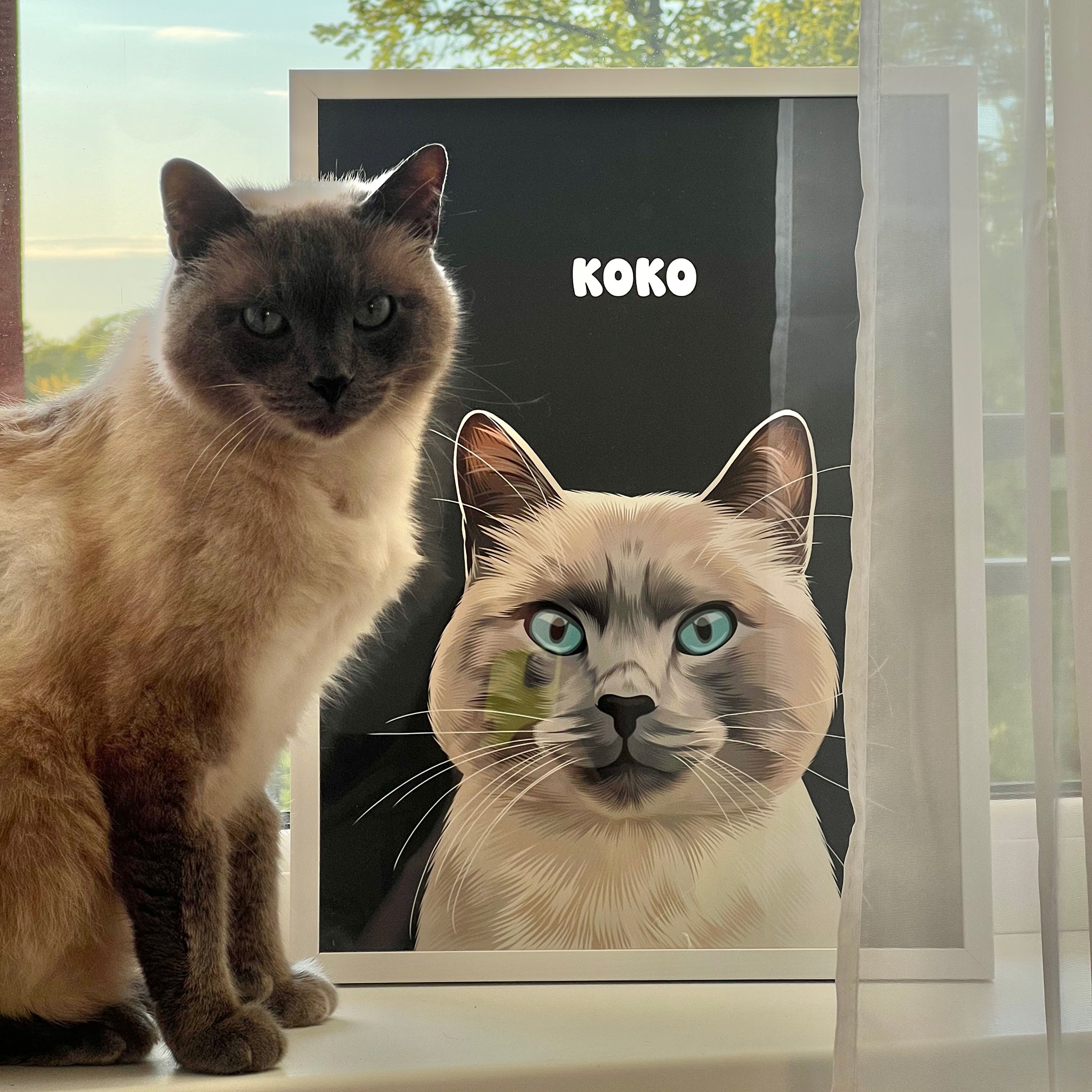 Photo of custom pet portrait framed poster with white-grey cat's artwork on it sitting next to the actual cat